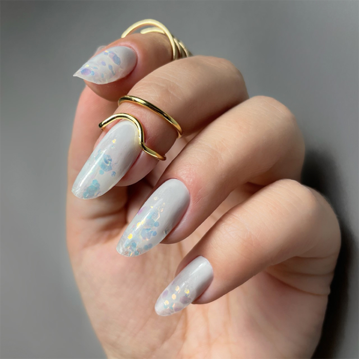Parelgrijze nagels met flakes en gouden ringen