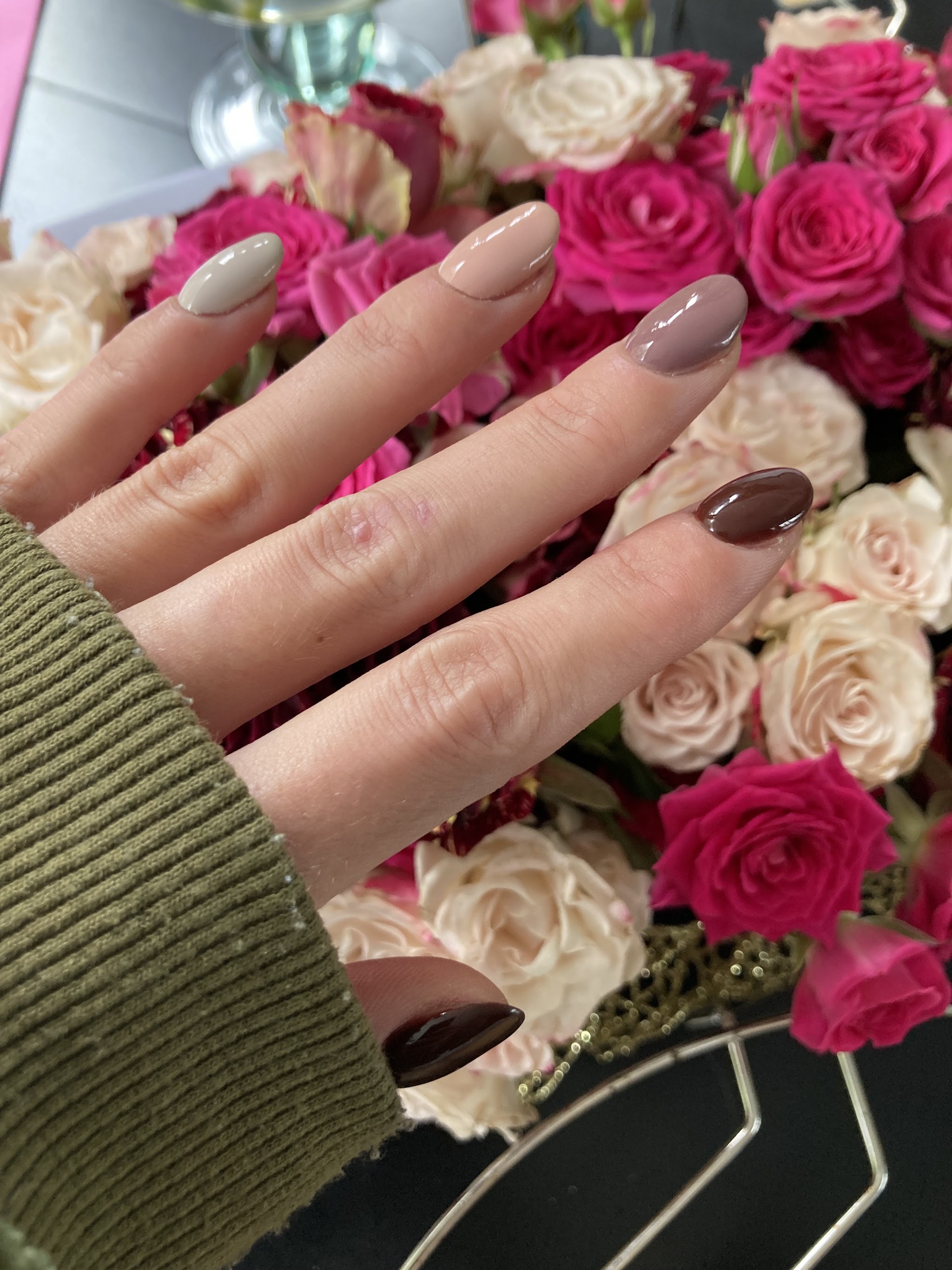 Taupe en nude nagels boven een boeket rozen